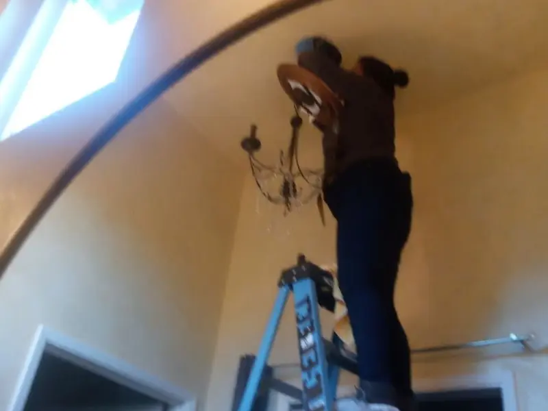 Electrician installing a chandelier in a Uniontown residence